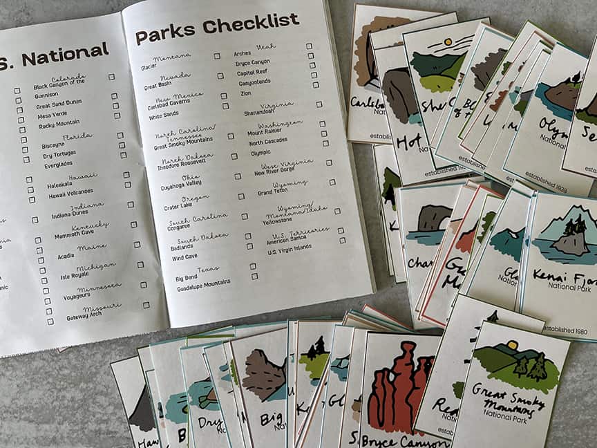 National Park journal opened to checklist pages with 63 National Parks cards s out around it
