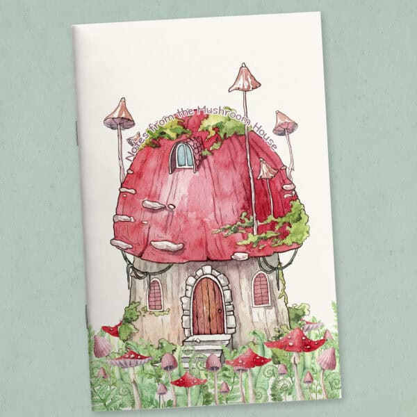 Printable journal cover page featuring a whimsical mushroom house with a curved title, shown as a folded and stapled booklet, with mushrooms and ferns illustrated on the cover.