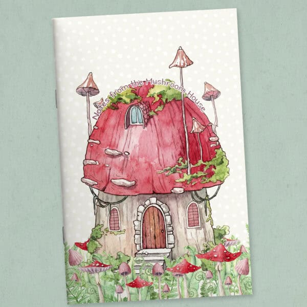 Printable journal cover page featuring a whimsical mushroom house with a curved title, shown as a folded and stapled booklet, with mushrooms and ferns illustrated on the cover.